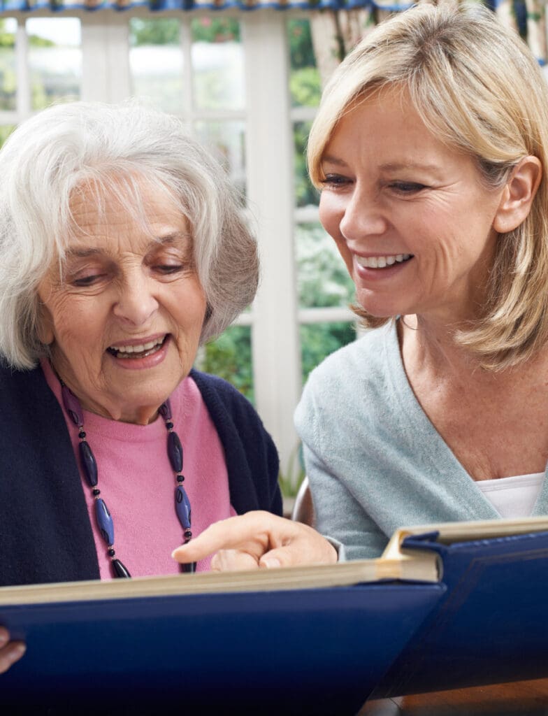A mother and daughter reading together, as part of a memory care activity in their apartment at The Delaney at The Vale in Woburn, MA.