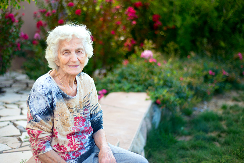 Beautiful smiling senior woman sitting in garden