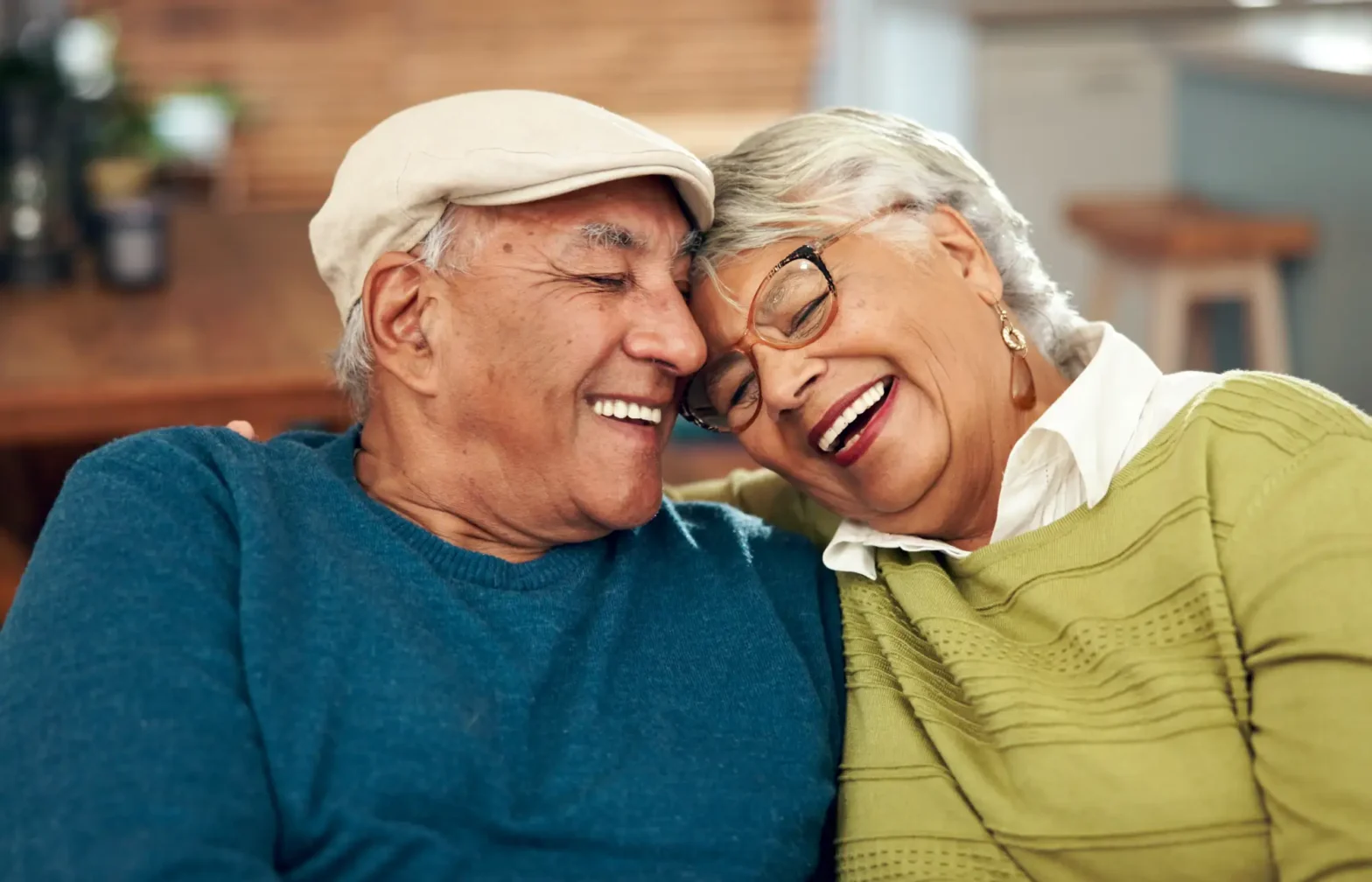 a senior couple leaning in towards each other while sitting on a couch