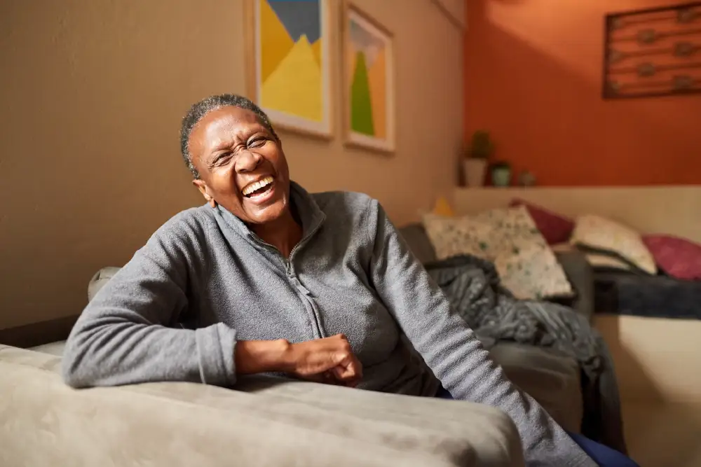a senior woman joyfully laughing in her living room