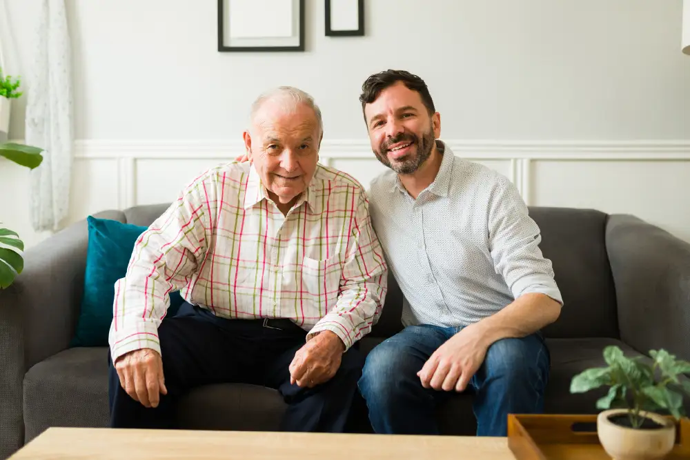 a man sitting on the couch with his senior father with dementia