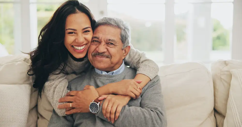 a senior man and his adult daughter hugging