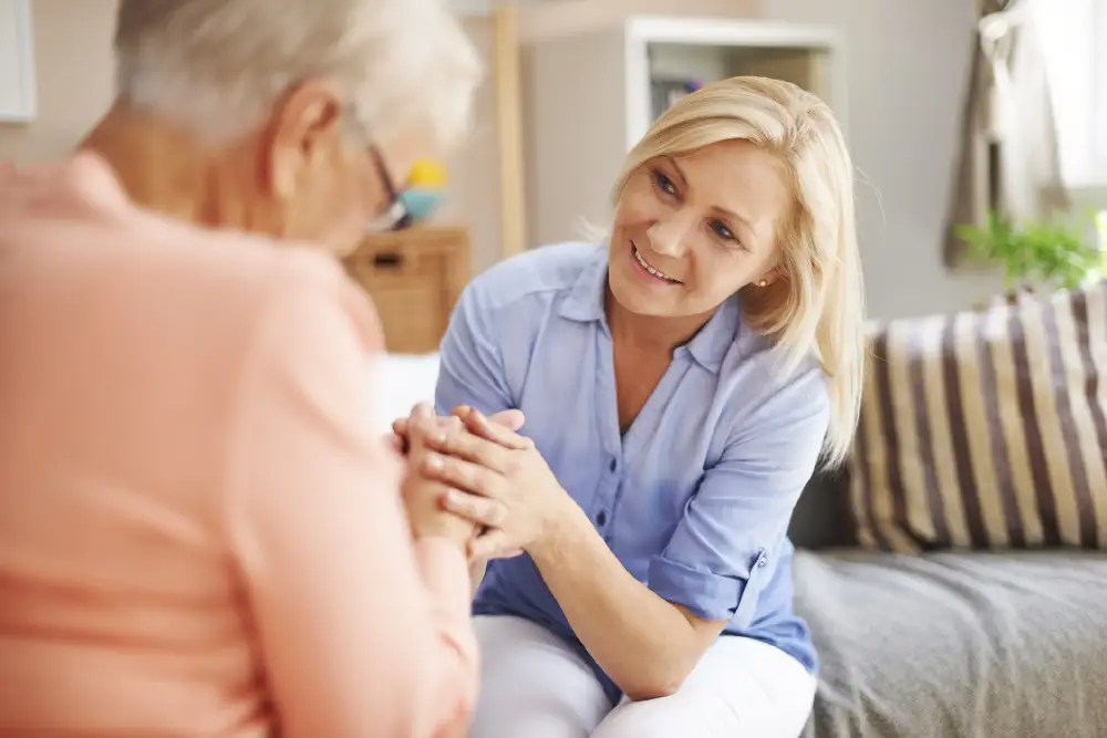a woman holding the hands of her senior mother with dementia