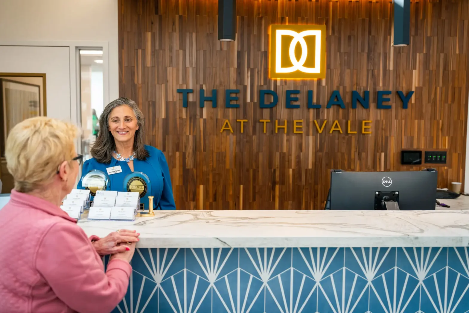 Employee at The Delaney at the Vale front desk helping senior