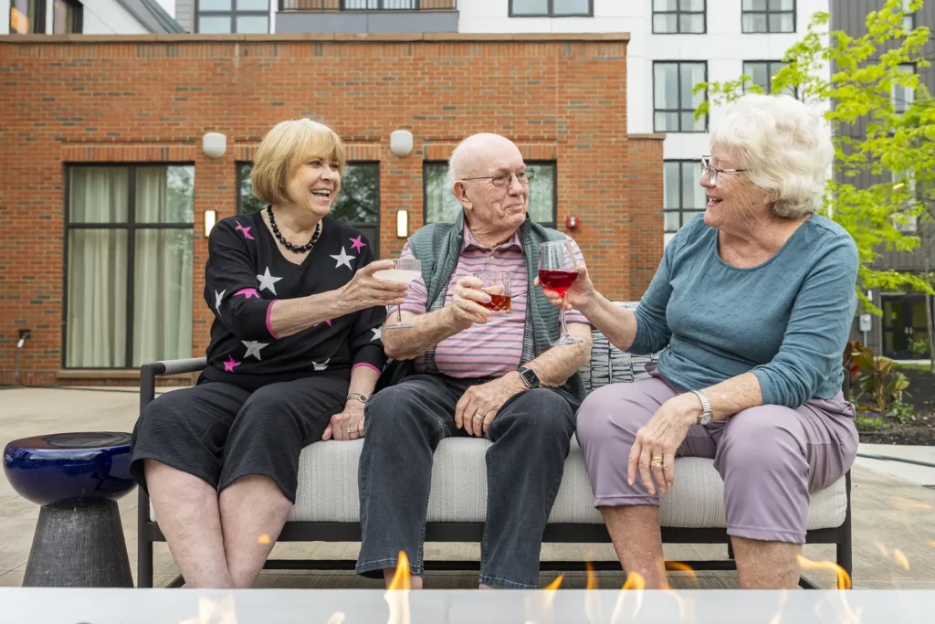 Three seniors toasting drinks in outdoor area at The Delaney at the Vale