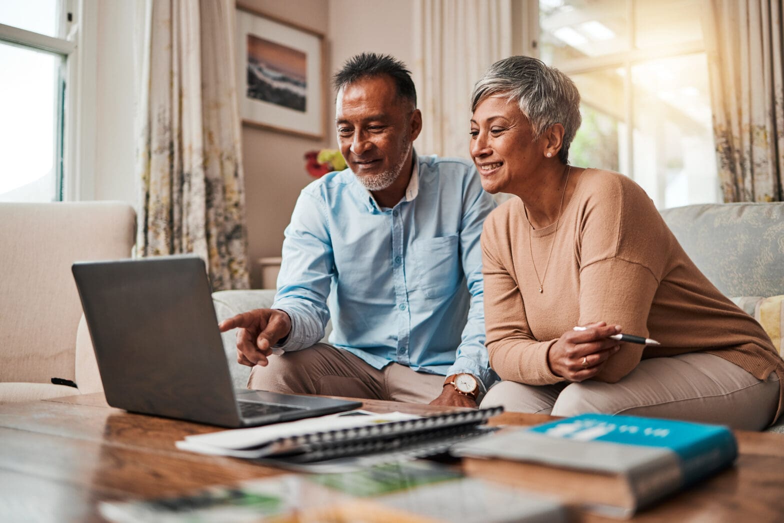 Senior man and woman on couch exploring levels of care for older adults on laptop