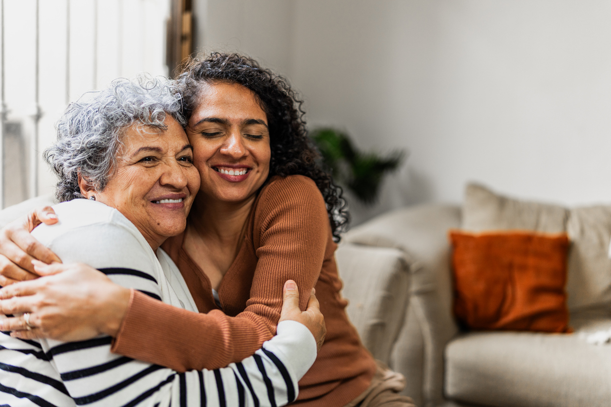 senior woman and family member hugging at home