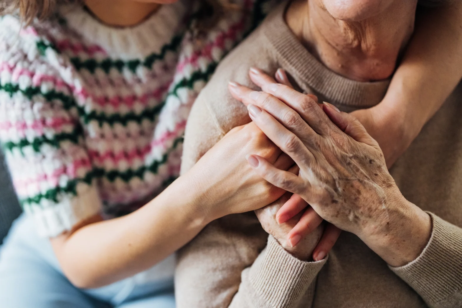 senior woman and adult daughter with hands on shoulder