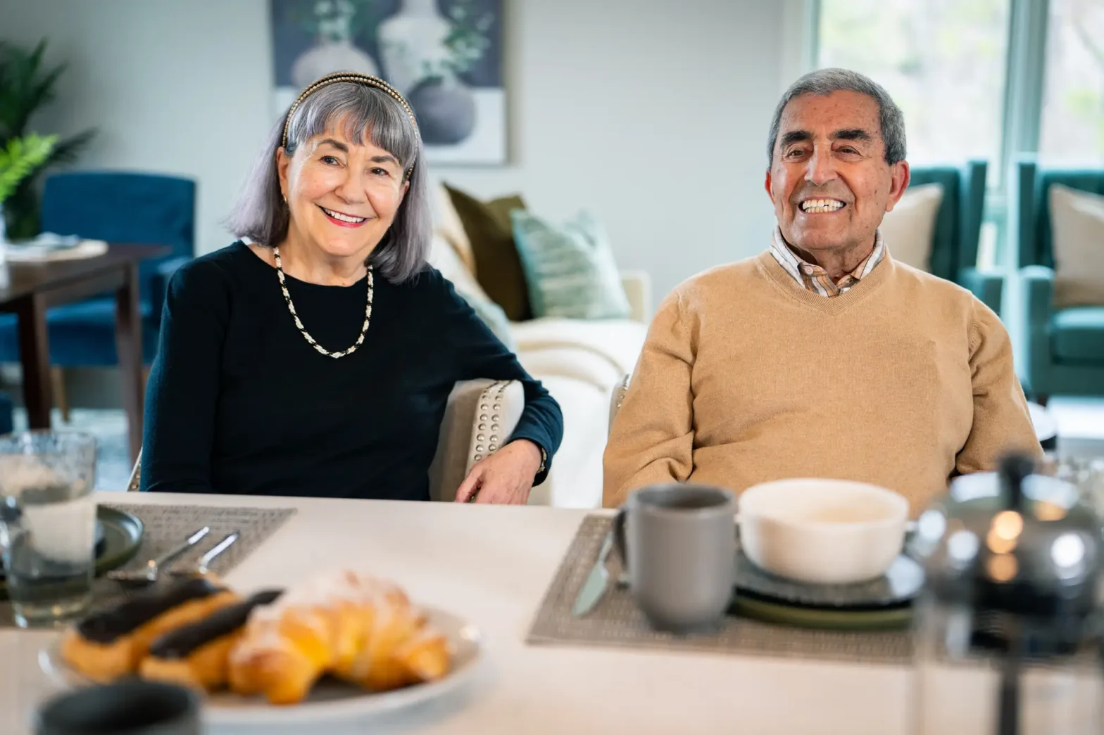 senior man and senior woman smiling at breakfast table after discussing the signs it's time for independent living and joining The Delaney at The Vale in Woburn, MA.