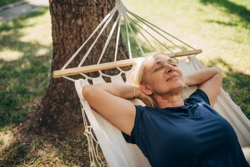 An elderly woman getting sleep on a hammock on the campus of The Delaney at the Vale in Woburn, MA.