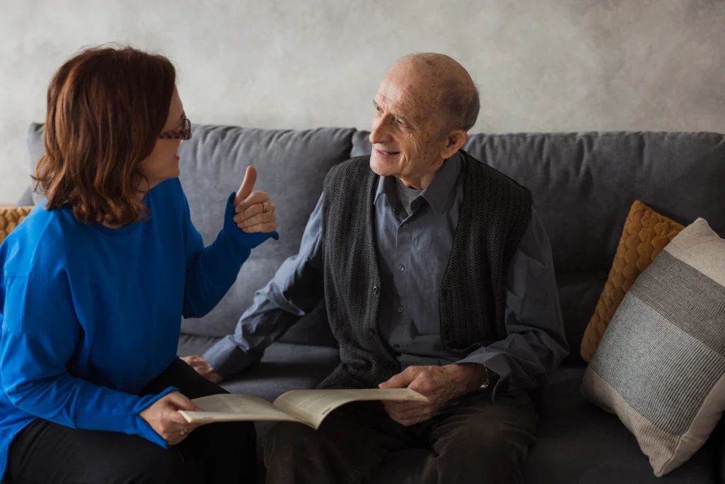 adult daughter and senior father looking at a book and discussing when to move from assisted living to memory care