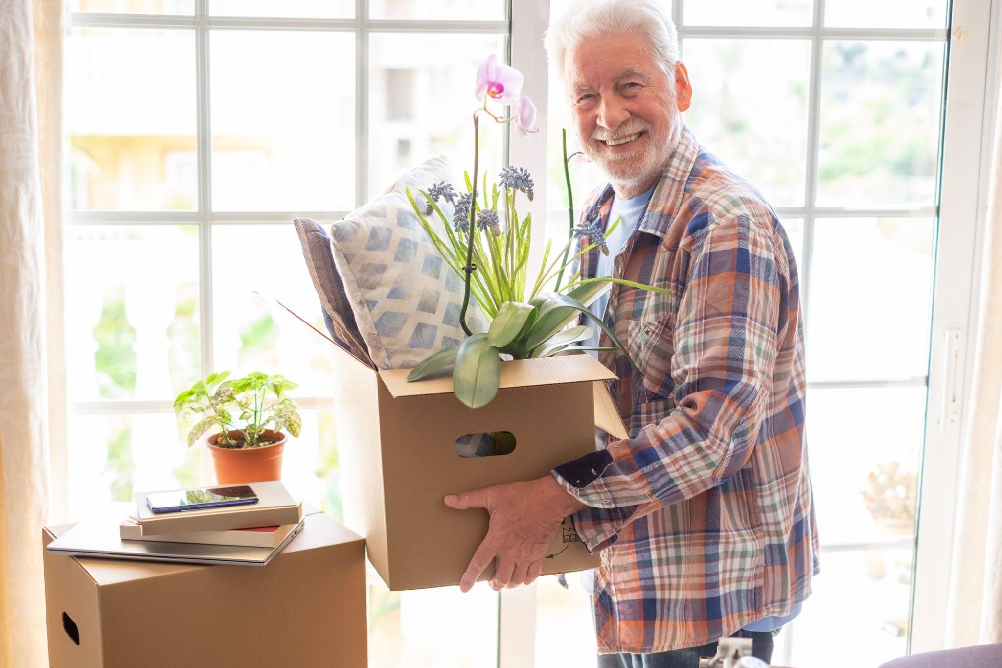 An elderly man from the Boston Area packing & preparing to move to senior living early at The Delaney at The Vale.