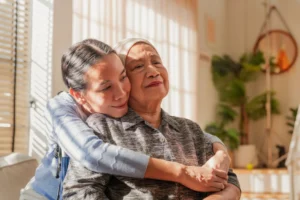 An adult daughter hugging her elderly mother while talking about caregiver burnout signs and needing additional daily support through senior living options in Woburn, MA.